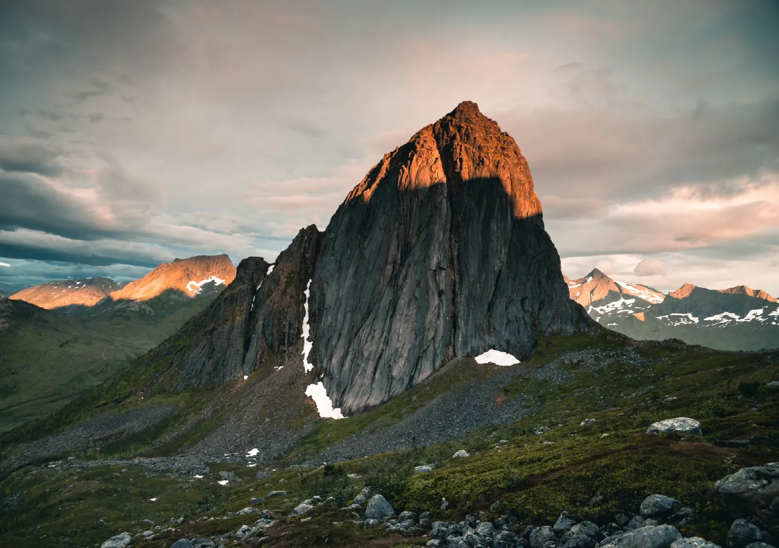 Segla's steep rock face lit by the evening sun above Fjordgård on Senja