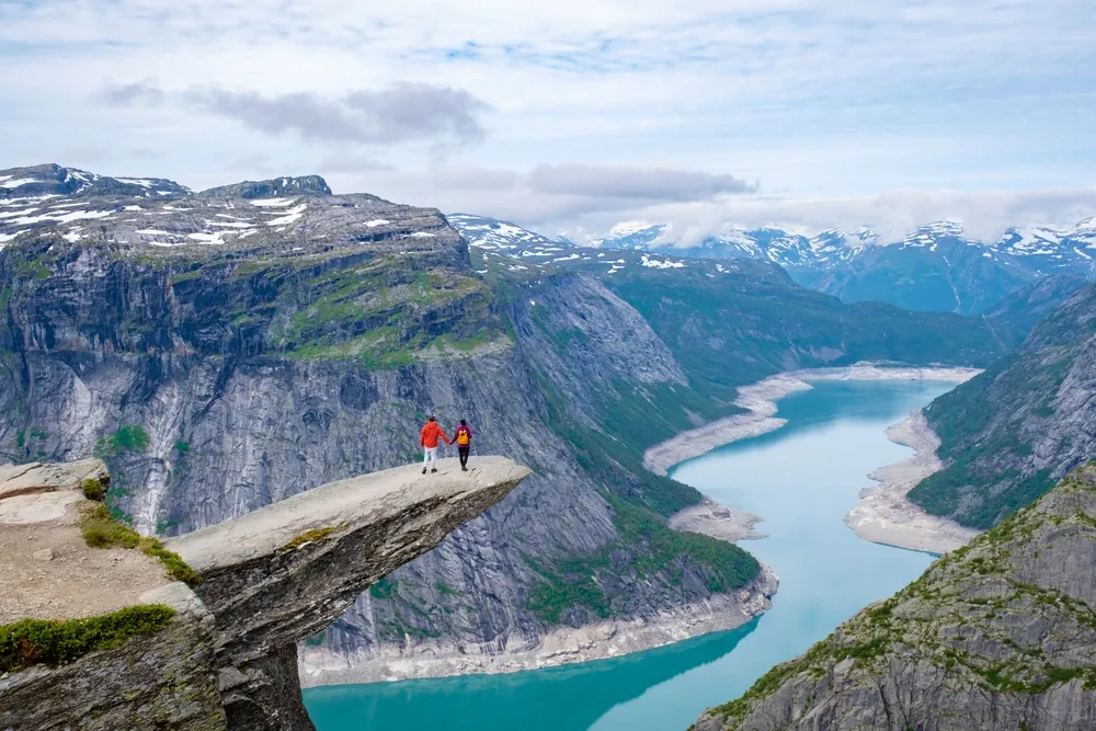 Two hikers on the Trolltunga rock formation above Ringedalsvatnet