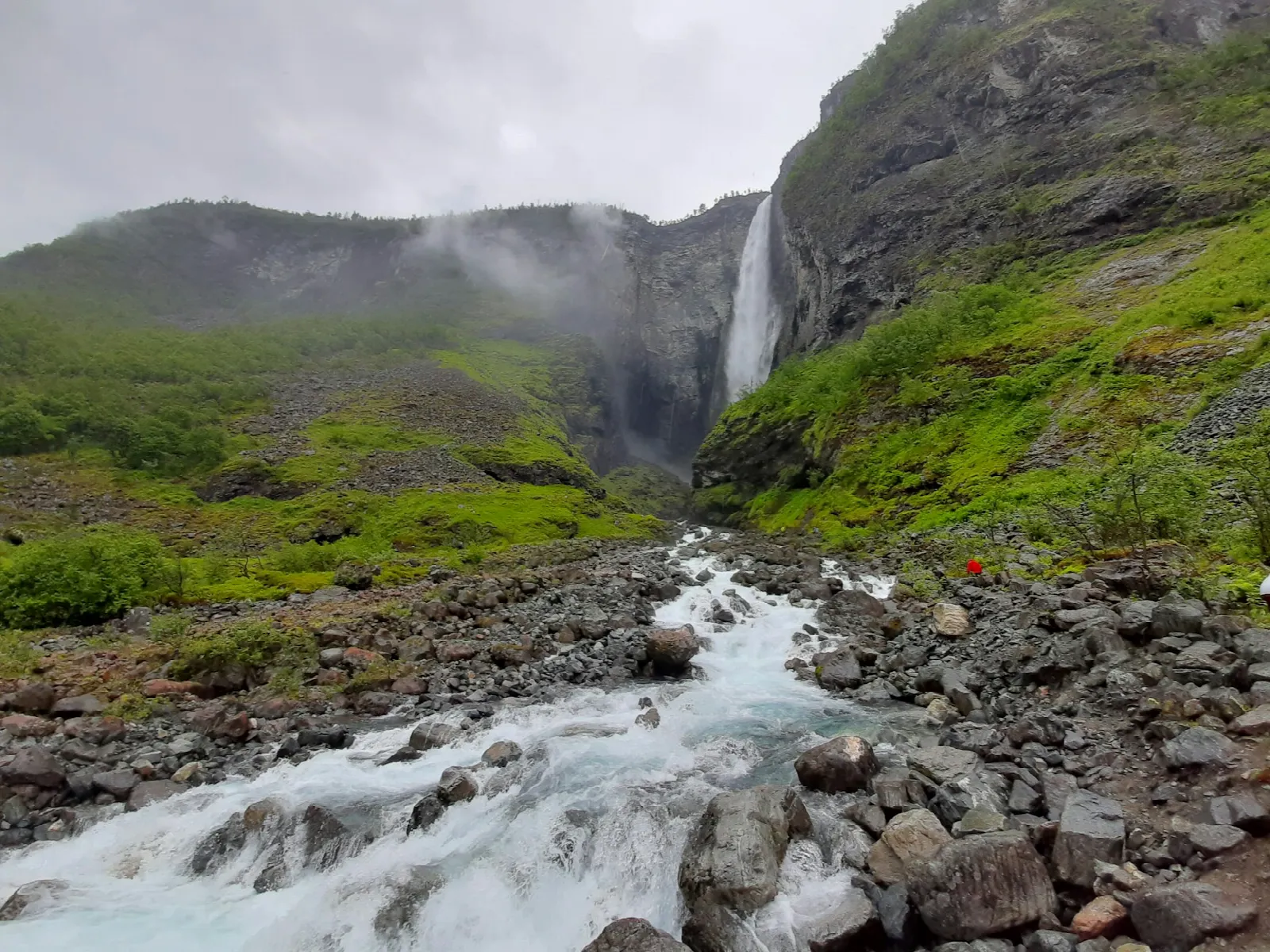 Vettisfossen plunging into the green Utladalen valley above its rocky outflow